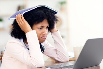 Bad Grade. Sad Black Girl At Laptop Covering Head With Exercise-Book During Online Class At Home.