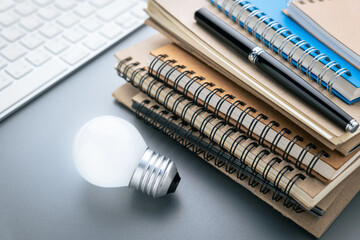 A lot of notebooks with glowing light bulb and a part of computer keyboard, use the content...