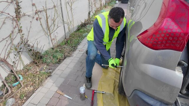 A guy changes tire on street to summer tire in nature
