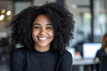 Obraz premium Portrait of a happy young African American woman sitting in her office chair, smiling confidently