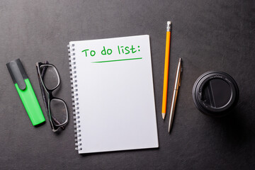Organized work desk setup with office supplies, coffee, and a notepad for writing a to-do list