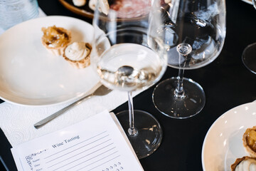 White wine glasses and gourmet bites set beside tasting notes during a wine education session. Emphasizes rustic elegance and terroir-driven culture