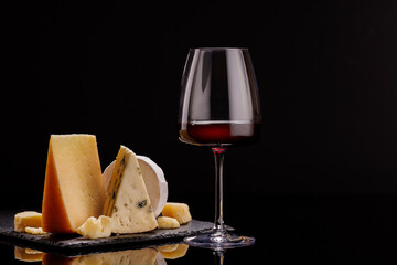 A refined selection of aged cheeses presented on a board, accompanied by a glasses of wine
