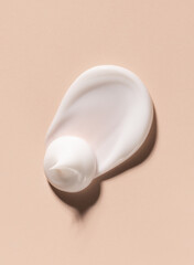 smear of creamy white texture cosmetic sample close up on beige background