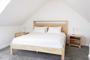 pristine bedroom features a light wood double bed with crisp white linens.