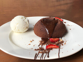 Chocolate Lava Cake with Melting Center and Vanilla Ice Cream, Served on White Plate with Wooden Background