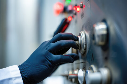 Gloved hand operating control panel with illuminated indicators