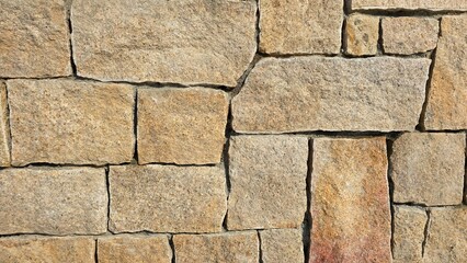 Close-up view of a rustic stone wall with rough textured blocks, perfect for backgrounds, construction, and architecture themes.