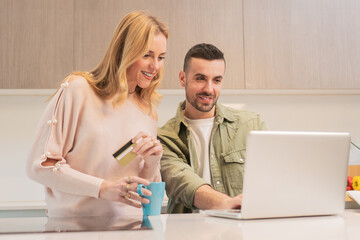 Couple engaging in online shopping activity while using a laptop and credit card to make a purchase...