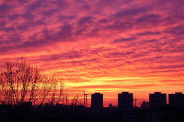 Fototapeta premium Sustainable energy wind turbines silhouetted by a stunning orange-pink sunrise sky