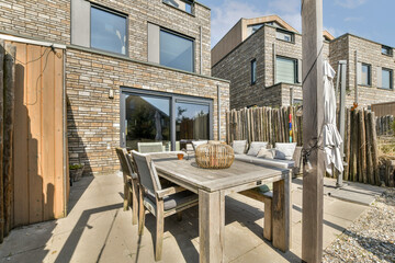 A stylish outdoor living area featuring contemporary wooden furniture, brick walls, and a cozy ambiance ideal for relaxation and social gatherings.