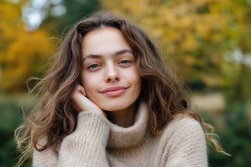 Fototapeta premium A woman with long brown hair is wearing a sweater and smiling. She is posing for a picture