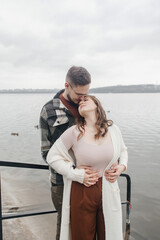 Fototapeta premium Young couple in stylish clothes on a walk. Romantic date outdoors. Walk, kisses and hugs