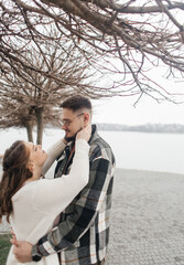 Fototapeta premium Young couple in stylish clothes on a walk. Romantic date outdoors. Walk, kisses and hugs