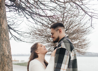 Young couple in stylish clothes on a walk. Romantic date outdoors. Walk, kisses and hugs