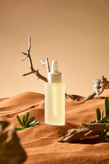 Serum dropper bottle placed on brown sand in barren wasteland. Dry tree branch winding and lying on sand fields. Desert shrubs grow lush in the dry sunny desert with many trunks scattered around.