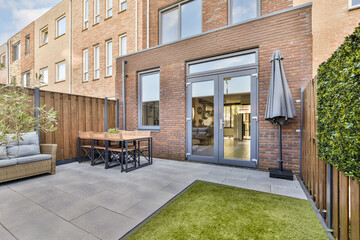 A contemporary outdoor patio featuring stylish furniture and a well-maintained garden area, ideal...