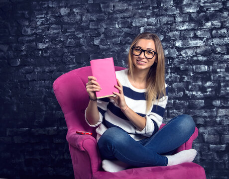 Young woman student. Girl reads a book. Pink book, pink chair - female readers club. library club