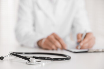 Doctor working and stethoscope on table in hospital, selective focus