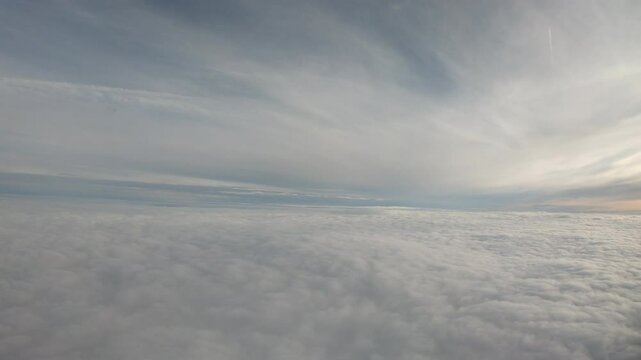 Faint golden hues sweep across high-altitude clouds, blending seamlessly into a dreamy sky viewed from the quiet airplane cabin.