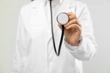 Doctor with stethoscope on light background, closeup