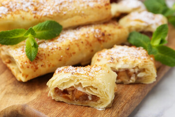 Tasty apple strudels with powdered sugar and mint on table, closeup