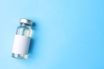 Hepatitis vaccine in glass vial on light blue background, top view. Space for text