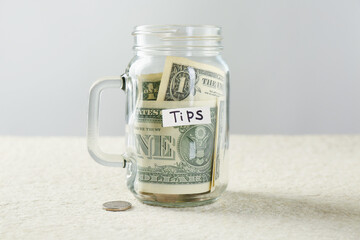 Mason jar with tips on light textured table against grey background, closeup