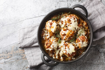 Skillet dinner inspired by the iconic French onion soup with caramelized onions, meatballs, and gooey cheese closeup on the table. Horizontal top view from above