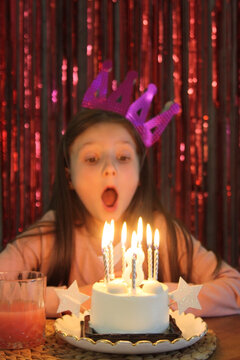 Girl celebrates birthday with candles and cake at home
