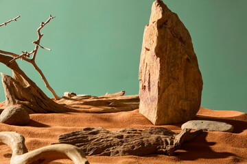 Rocks with sharp peaks and rough edges, standing like high mountains. Pebbles scattered around with dry branches. Sand beach with sand grains, uneven surface. Green background, wild desert concept.