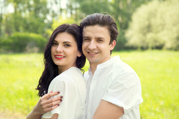 Fototapeta premium Spring love story of a young man and woman embracing each other on nature surrounded by flowering trees.
