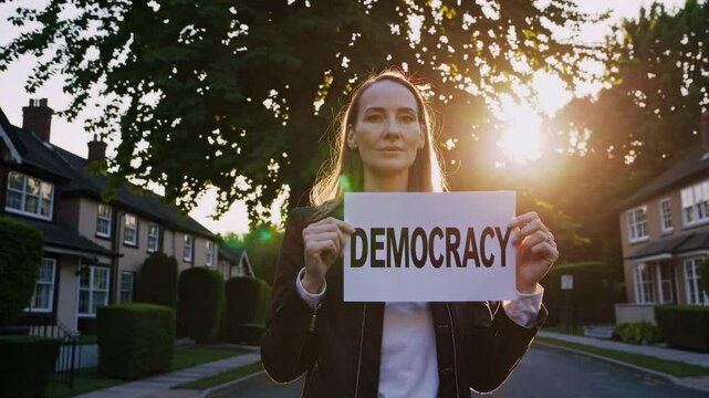 Woman holding democracy sign in quiet residential street, peaceful protest scene