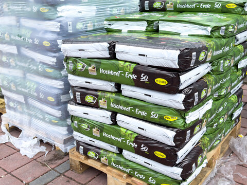 Stacks of hochbeet erde gardening soil bags on wooden pallets outdoors