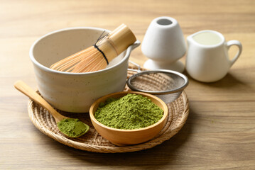Matcha green tea powder with tea bowl and chasen on wooden background