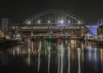 Obraz premium Stunning night view of the Newcastle upon tyne with Tyne bridge, Swing bridge and The High level bridge spanning the River Tyne connecting Newcastle upon tyne and Gateshead in North East England.