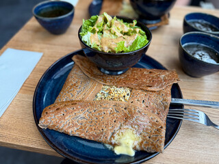 Traditional Crepe Galette made from buckwheat flour with cheese and nuts on a plate with salad in Brittany, France