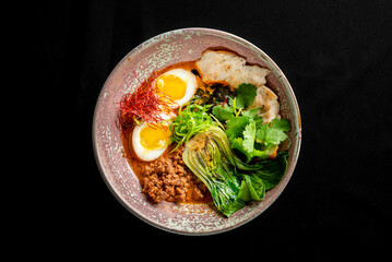 A beautifully arranged bowl of ramen featuring vibrant toppings: soft-boiled eggs, minced meat, bok choy, and fresh herbs, creating a rich and appetizing culinary experience