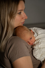 Caring mom holds her newborn baby close in a cozy indoor setting, emphasizing their bond and affection during a quiet moment together
