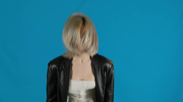 Angry young woman waves arms furiously expressing frustration silently. Blonde female in bad mood overwhelms by anger jumping up slow motion