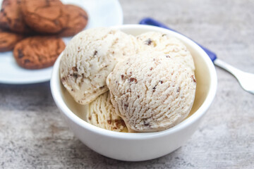 a bowl of vanilla scoop ice cream, with chocolate chip cookies