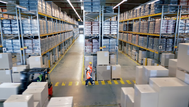 A bird's-eye view of a bustling warehouse reveals workers navigating aisles, highlighting the complex logistics of global supply chains.