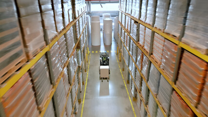 Obraz premium Aerial view of a vast warehouse with towering shelves filled with packages, highlighting the scale of global supply and logistics operations.