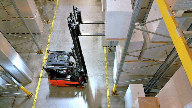 A forklift navigates an aisle in a warehouse, highlighting the precision and efficiency of logistics operations.