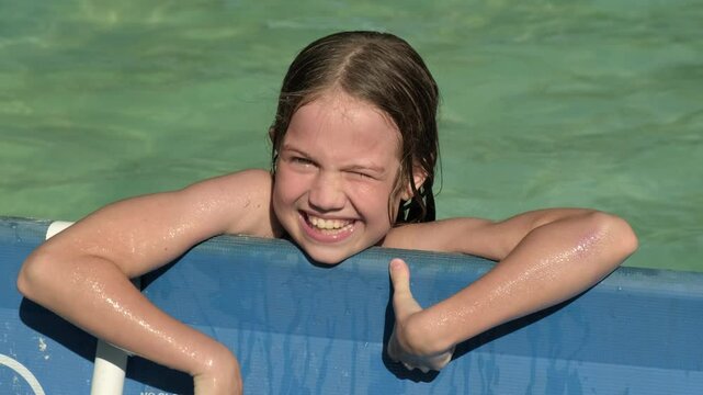 Portrait of smiling kid girl in frame swimming pool close up. Summer healthy outdoor activity for children. Child having fun
