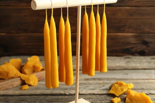 Hand dipped beeswax candles drying on rack on wooden table