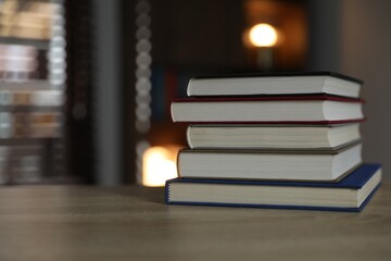 Stack of books on wooden table indoors. Space for text