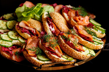 The platter of gourmet sandwiches topped with smoked salmon, crisp cucumbers, and vibrant greens.