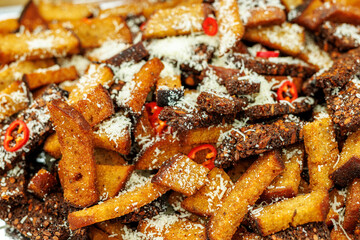 Toasted bread pieces topped with grated cheese and slices of red chili peppers.