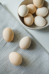 Fresh farm chicken eggs in a bowl and on a kitchen grey towel